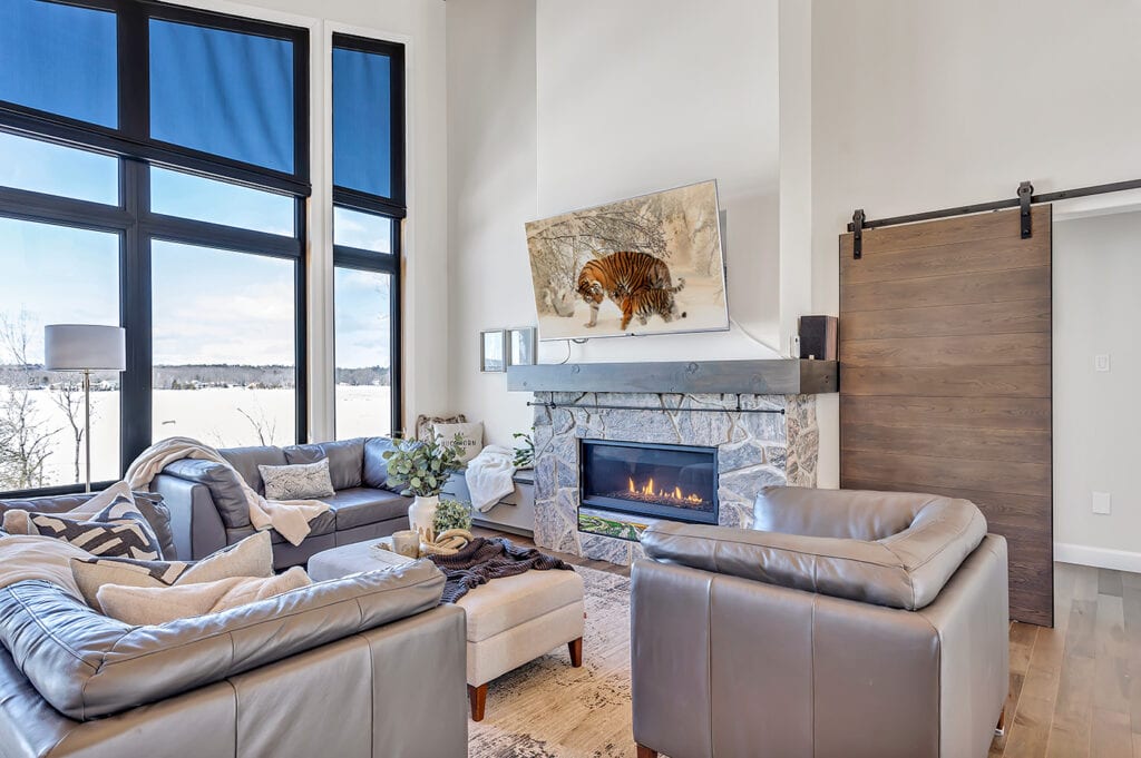 living room with stone fireplace and large window overlooking lake